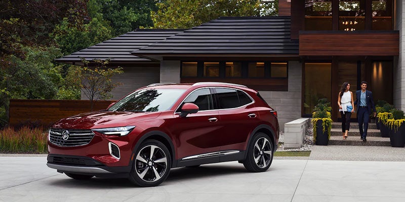 A dark red Buick Envision parked in front of a house
